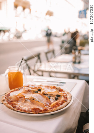 Italian pizza and orange juice on outdoor restaurant table Italian pizza and orange juice on outdoor restaurant table 137207039