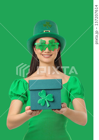 Young woman in green holds a gift for St. Patrick's Day Young woman in green holds a gift for St. Patrick's Day 137207614