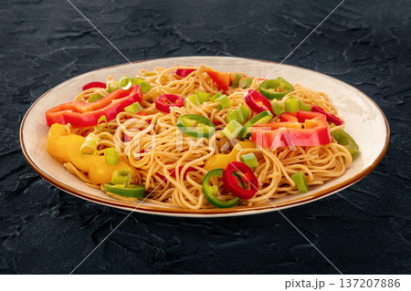 Hakka noodles with vegetables, peppers and green onions, on black 137207886