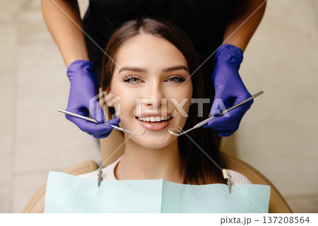 Happy patient during a visit to the dentist. The doctor is checking teeth using a dental instrument, ensuring proper oral care in the dentistry clinic Happy patient during a visit to the dentist. The doctor is checking teeth using a dental instrument, ensuring proper oral care in the dentistry clinic 137208564