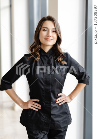 Young female doctor is standing in a hospital hall and looking at the camera 137208597
