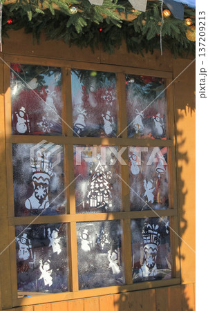Christmas window decorated with festive stencils and artificial snow at a traditional winter market. Christmas window decorated with festive stencils and artificial snow at a traditional winter market. 137209213