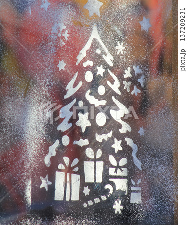 Festive macro of a Christmas tree stencil with gifts on a window decorated with white snow spray. 137209231