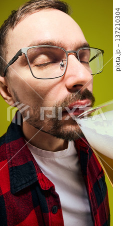 Man with foam mustache drinking light beer close up portrait against yellow background. 137210304