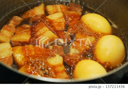 鍋で煮込んでいる豚の角煮と煮卵 鍋で煮込んでいる豚の角煮と煮卵 137211436