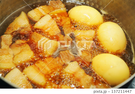 鍋で煮込んでいる豚の角煮と煮卵 137211447
