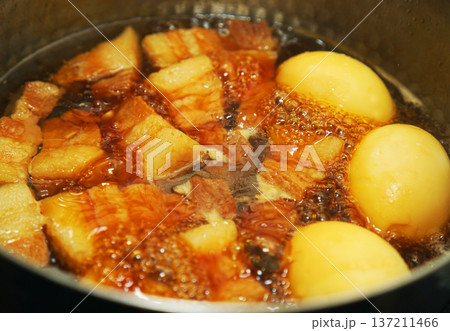 鍋で煮込んでいる豚の角煮と煮卵 137211466
