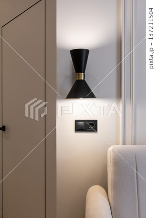 Black wall sconce above modern sofa corner Black wall sconce above modern sofa corner 137211504