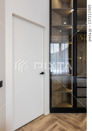 Modern white door beside glass wardrobe closet 137211505