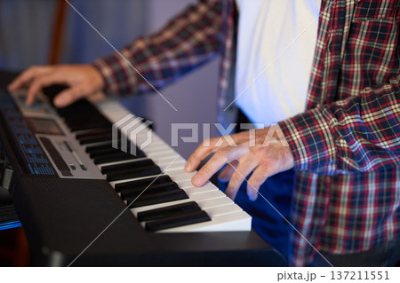 A close-up of hands playing a digital keyboard synthesizer A close-up of hands playing a digital keyboard synthesizer 137211551