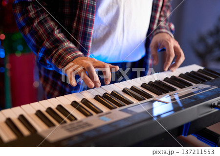 A close-up of hands playing a digital keyboard synthesizer A close-up of hands playing a digital keyboard synthesizer 137211553