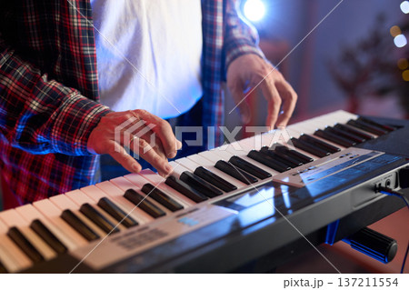 A close-up of hands playing a digital keyboard synthesizer A close-up of hands playing a digital keyboard synthesizer 137211554