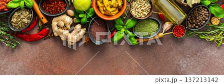 A rich palette of colorful spices and herbs, resting on a brown background, radiating freshness and an inviting aroma, perfect for gourmet inspiration, banner 137213142