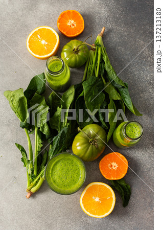 Juice is being made from fresh greens like spinach, chard, and broccoli along with oranges and tangerines. The process takes place in summer with bright colors and natural ingredients Juice is being made from fresh greens like spinach, chard, and broccoli along with oranges and tangerines. The process takes place in summer with bright colors and natural ingredients 137213180