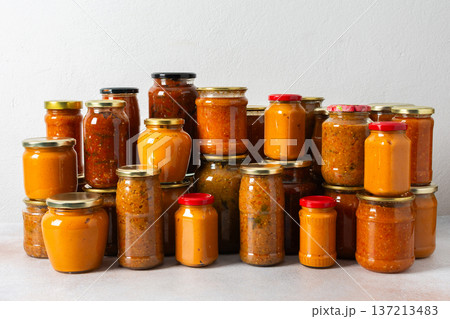 Various jars filled with home-canned vegetables are lined up in preparation for winter. The colorful jars showcase a range of preserved foods ready to be used when fresh produce is scarce Various jars filled with home-canned vegetables are lined up in preparation for winter. The colorful jars showcase a range of preserved foods ready to be used when fresh produce is scarce 137213483