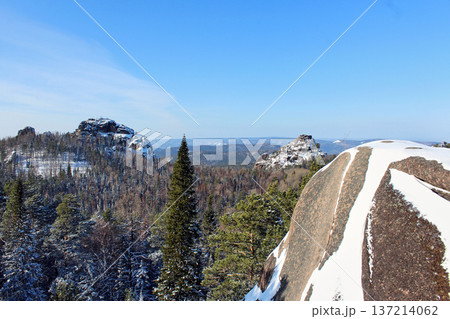Wide panoramic view of Krasnoyarsk Stolby national park in winter with snow-covered rocks and forest. Nature scenery for travel and tourism. Rocks First Pillar, Second Pillar. View from Fourth Pillar. Wide panoramic view of Krasnoyarsk Stolby national park in winter with snow-covered rocks and forest. Nature scenery for travel and tourism. Rocks First Pillar, Second Pillar. View from Fourth Pillar. 137214062