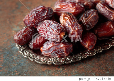 Dried dates fruit in silver tray on a rustic background. Dried dates fruit in silver tray on a rustic background. 137215216