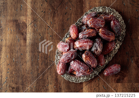 Dried dates fruit in silver tray on a wooden table. Dried dates fruit in silver tray on a wooden table. 137215225