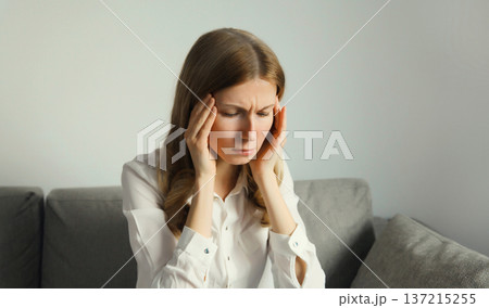 Exhausted tired woman suffering from headache, stress, fatigue, temples pain, migraine, loud noise Exhausted tired woman suffering from headache, stress, fatigue, temples pain, migraine, loud noise 137215255