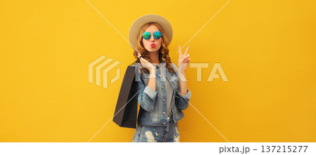 Stylish beautiful happy woman standing with colorful shopping bags posing on vivid yellow wall 137215277