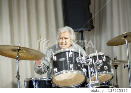 Senior woman enjoying her hobby playing drums. 137215535