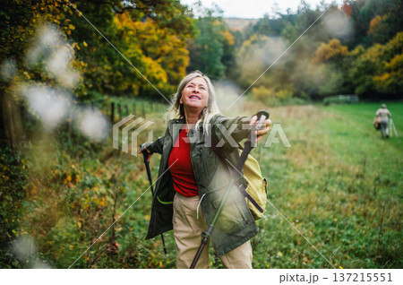 Happy senior woman on nature walk with trekking sticks. Happy senior woman on nature walk with trekking sticks. 137215551