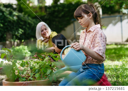 Portrait of cute schoolgirl taking care of plants in school garden during at outdoor sustainable education class. Concept of experiential learning and ecoliteracy. 137215681