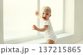 Little baby looking out the window in white room at home 137215865