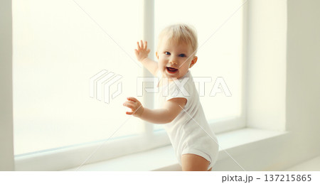 Little baby looking out the window in white room at home 137215865