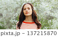 Lovely young woman in spring blooming garden with white flowers on the trees in park 137215870