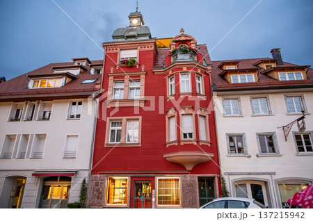 Wangen, germany, august 17, 2023. Historic red building featuring an ornate facade, bay windows, and a small turret against a blue sky at dusk in wangen im allgau Wangen, germany, august 17, 2023. Historic red building featuring an ornate facade, bay windows, and a small turret against a blue sky at dusk in wangen im allgau 137215942
