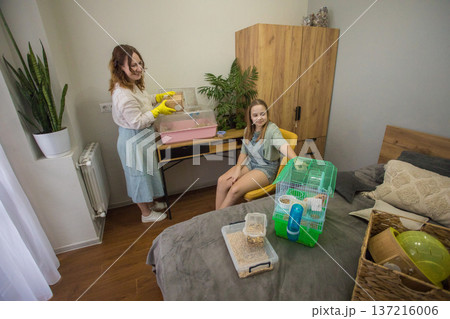 Two people care for small animals in a cozy room during the day while engaging Two people care for small animals in a cozy room during the day while engaging 137216006