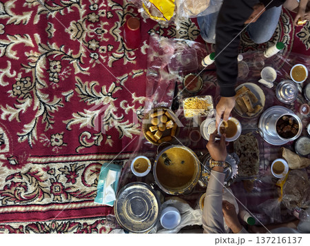 Realistic top view photograph of a traditional Arab family gathering around the table while preparing and sharing iftar during Ramadan. Authentic Ramadan atmosphere, traditional dishes, cultural Realistic top view photograph of a traditional Arab family gathering around the table while preparing and sharing iftar during Ramadan. Authentic Ramadan atmosphere, traditional dishes, cultural 137216137