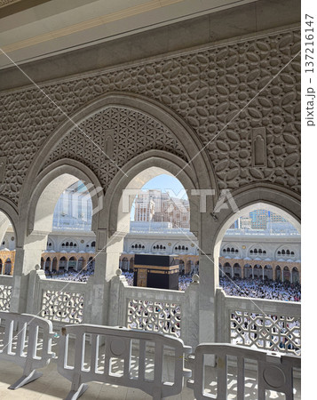View of the Kaaba and pilgrims at Masjid al-Haram in Mecca through ornate stone arches 137216147