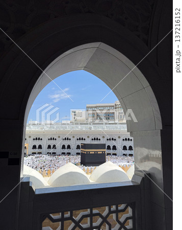 View of the Kaaba and pilgrims in Masjid al-Haram framed by an arched window in Mecca View of the Kaaba and pilgrims in Masjid al-Haram framed by an arched window in Mecca 137216152