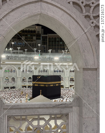 Night view of the Kaaba in Mecca framed by an ornate marble arch with pilgrims around tawaf Night view of the Kaaba in Mecca framed by an ornate marble arch with pilgrims around tawaf 137216173