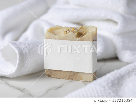 Mockup of beige solid soap bar with blank paper label near white bath towel, personal care packaging Mockup of beige solid soap bar with blank paper label near white bath towel, personal care packaging 137216354