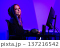 Young woman gaming at a stylish setup with vibrant purple lighting 137216542
