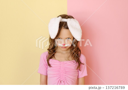 An angry, disgruntled Child in an Easter bunny costume glares maliciously from under his forehead 137216789