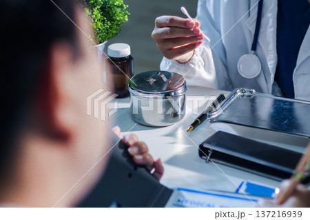 Medical team having a meeting with doctors in white lab coats and surgical scrubs seated at a table discussing a patients working online using computers in the medical industry. Medical team having a meeting with doctors in white lab coats and surgical scrubs seated at a table discussing a patients working online using computers in the medical industry. 137216939
