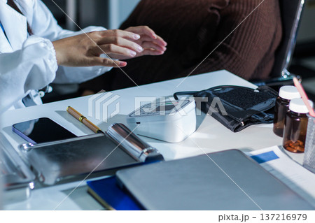A doctor's hands carefully taking a patient's blood pressure using a sphygmomanometer. A doctor's hands carefully taking a patient's blood pressure using a sphygmomanometer. 137216979