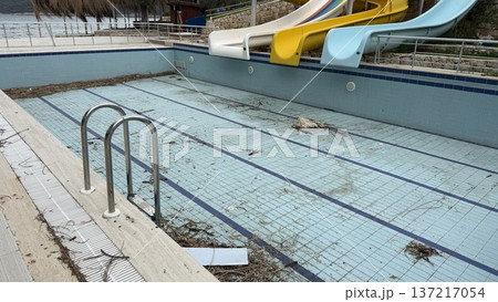 Empty swimming pool with debris in off-season outdoor area showing neglect and disuse 137217054