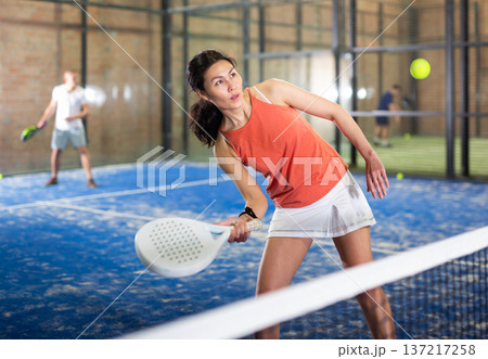 Young asian woman playing padel on a hard court Young asian woman playing padel on a hard court 137217258