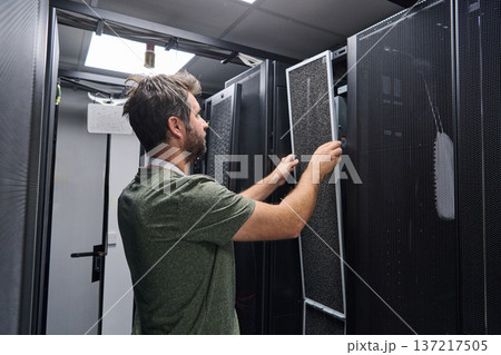 Data center technician replaces air filter in server rack during routine IT maintenance and hardware check 137217505