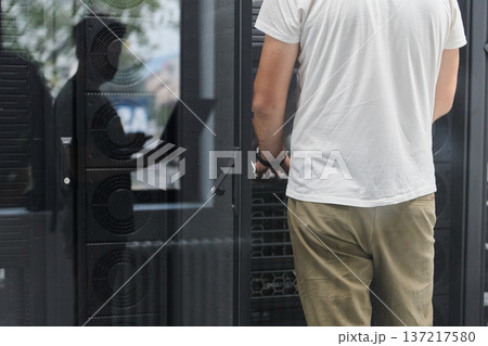 IT technician working on server rack in data center performing hardware maintenance and inspection 137217580