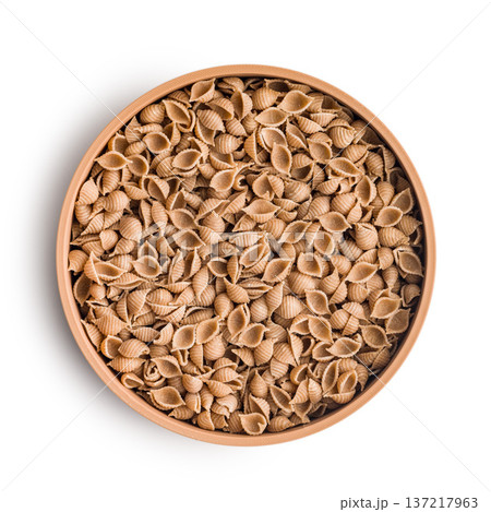 Wholegrain conchiglie pasta in bowl isolated on white background. Wholegrain conchiglie pasta in bowl isolated on white background. 137217963