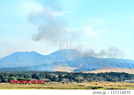 阿蘇山の野焼き風景を走る赤い列車 137218070