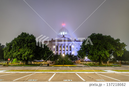Scenic night view of the illuminated classical facade and dome of the Oklahoma State Capitol building from an empty parking lot on a foggy night in Oklahoma City, Oklahoma, United States. 137218082