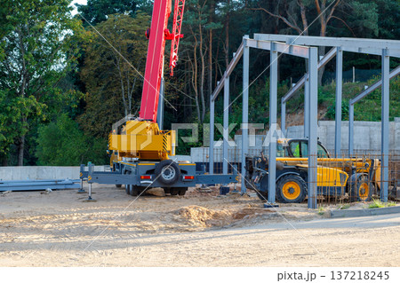 Orange mobile crane and telescopic handler. Construction equipment at the construction site of a building under construction Orange mobile crane and telescopic handler. Construction equipment at the construction site of a building under construction 137218245