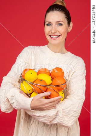 Smiling and happy young woman with fruits in hands Smiling and happy young woman with fruits in hands 137218468